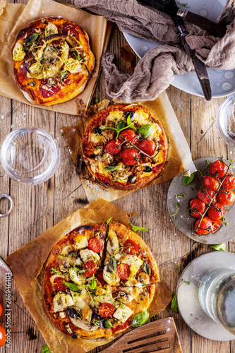 Fresh selfmade mini pizza on rustic wooden oak table 