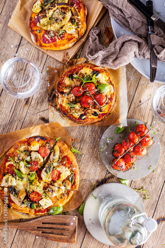 Fresh selfmade mini pizza on rustic wooden oak table 