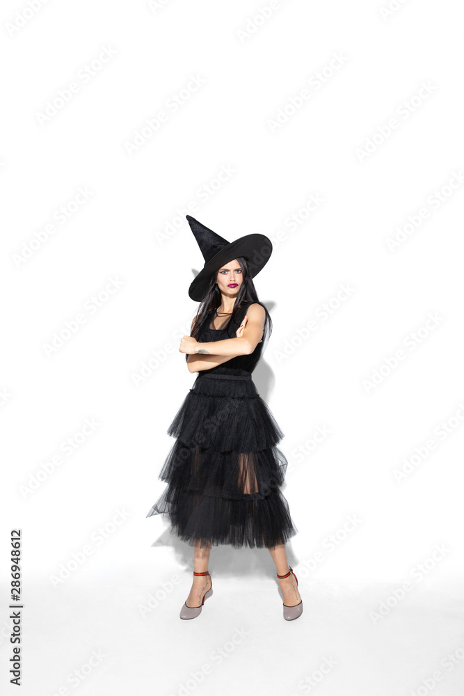 Young brunette woman in black hat and costume on white background. Attractive caucasian female model. Halloween, black friday, cyber monday, sales, autumn concept. Copyspace. Standing hands crossed. Young brunette woman in black hat and costume on white background. Attractive caucasian female model. Halloween, black friday, cyber monday, sales, autumn concept. Copyspace. Standing hands crossed.