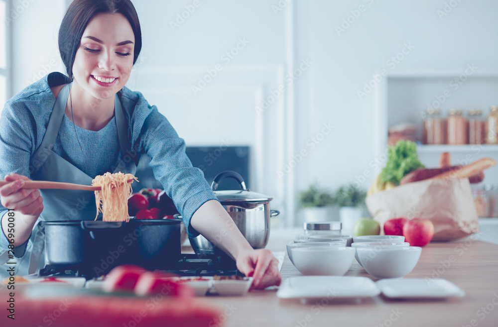 Obraz premium Cooking woman in kitchen with wooden spoon