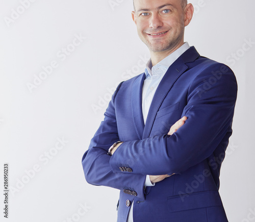 Cuadro en lienzo Handsome businessman standing with arms crossed on grey background