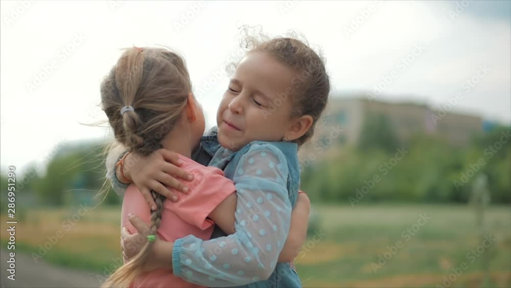 Two smiling, curly, cute sisters baby-girls hug tightly each other. Happy childhood, positive emotions, true feelings.