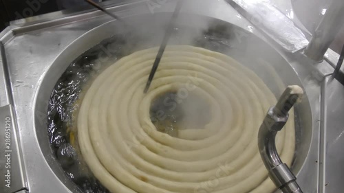 Frying Churros in deep oil in churreria, traditional dough pastry snack. Churros are popular mostly in Spain, dipped in champurrado, hot chocolate, dulce de leche or cafe con leche. photo