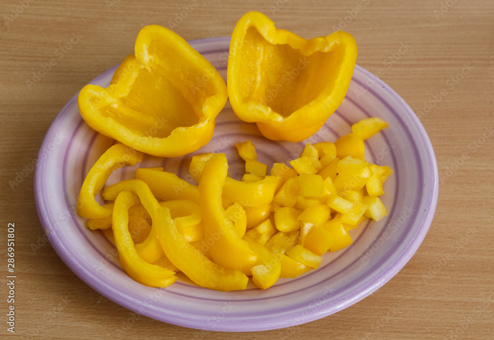 Half and pieces of yellow pepper on a purple plate Half and pieces of yellow pepper on a purple plate
