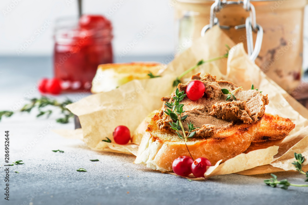 Delicious pate of chicken liver and meat on grilled toasts with cranberries and thyme, gray kitchen table background, space for text, selective focus Delicious pate of chicken liver and meat on grilled toasts with cranberries and thyme, gray kitchen table background, space for text, selective focus