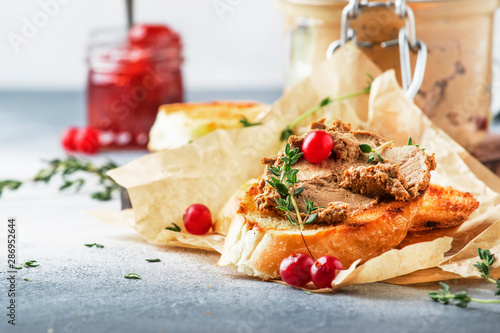 Delicious pate of chicken liver and meat on grilled toasts with cranberries and thyme, gray kitchen table background, space for text, selective focus