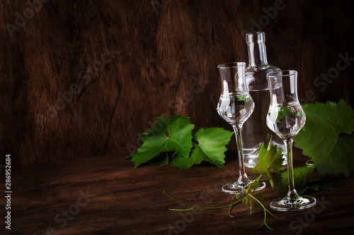 Grape vodka, pisco - traditional Peruvian strong alcoholic drink in elegant glasses on vintage wooden table, copy space photo