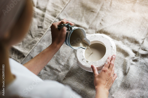 Female hands pour pottery mixture into a mold. Shaped method for making clay dishes. Handwork. Pottery making