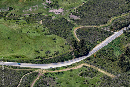 Aerial View of an Isolated Rural Highway Cutting through the Green Mountains and Farms in San Mateo County, California, USA