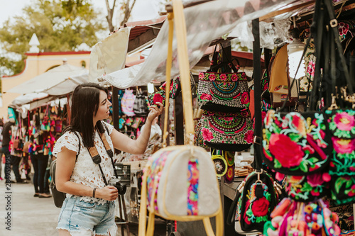 traveler girl buying souvenirs in the traditional Mexican market in Mexico streets, hispanic tourists standing in outdoor Latin America