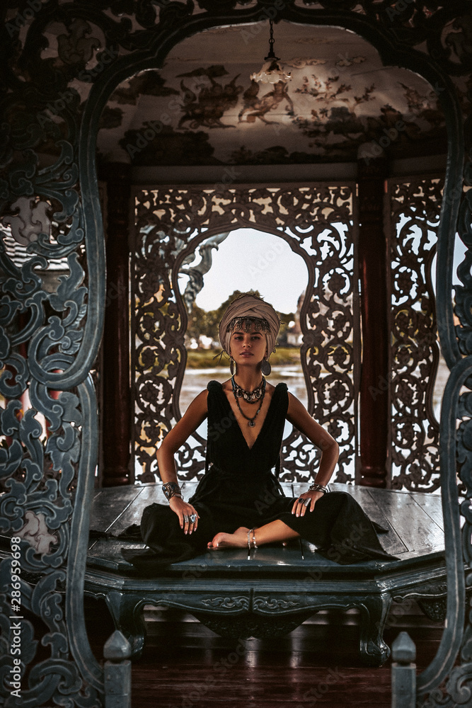 Obraz premium beautiful young woman in elegant black dress wearing turban. oriental princess