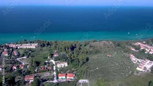 Aerial view of turquoise and blue sea coast and tourist homes in Kriopigi, Halkidiki Greece, side movement by drone photo