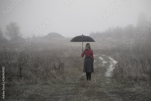 young girl with umbrella in autumn field