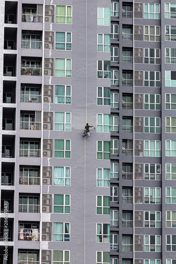 A painter was climbing the new building to painted on the facade of a high-rise building A painter was climbing the new building to painted on the facade of a high-rise building