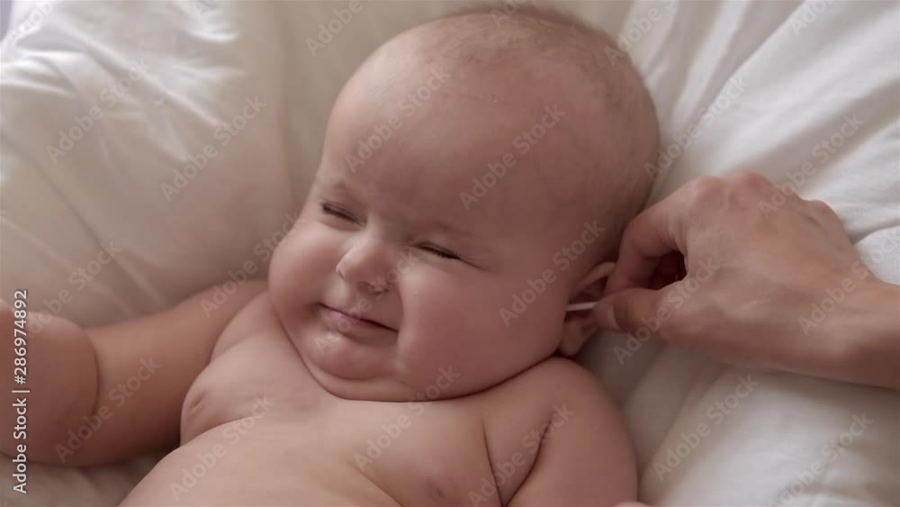 Mother cleans the ears of her newborn baby. Mother cleans the ears of her newborn baby.
