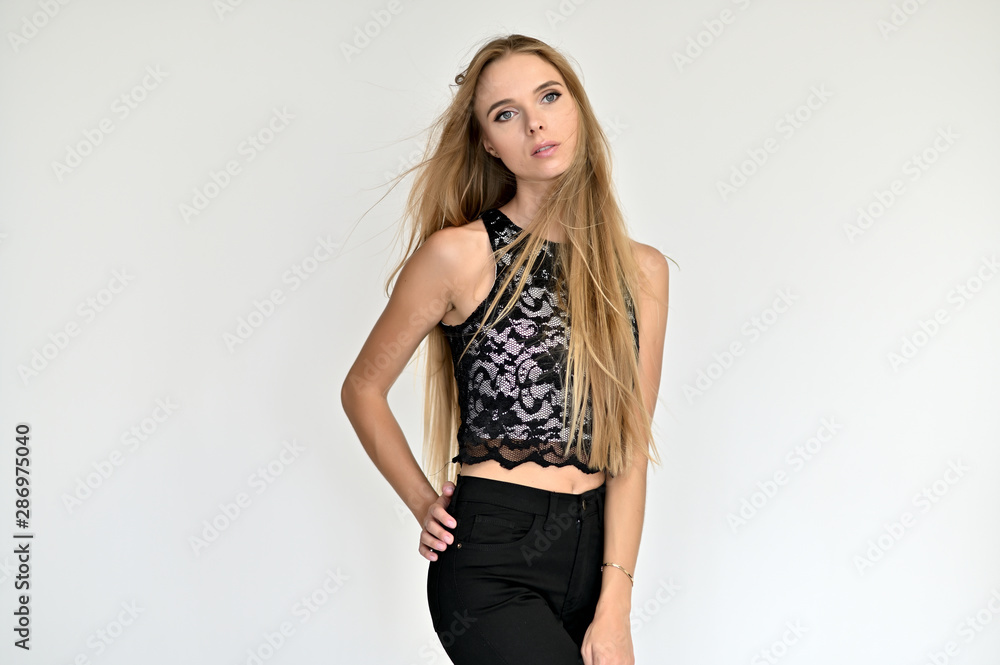 Portrait of a beautiful pretty girl in a gray T-shirt with long curly hair on a white background. Beauty and brightness. Shows hands to the side, smiles with different emotions. Portrait of a beautiful pretty girl in a gray T-shirt with long curly hair on a white background. Beauty and brightness. Shows hands to the side, smiles with different emotions.