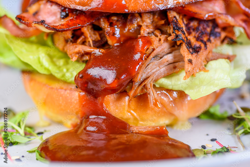 A Pulled Pork Burger with bacon, lettuce and barbecue sauce in a bead bun A Pulled Pork Burger with bacon, lettuce and barbecue sauce in a bead bun