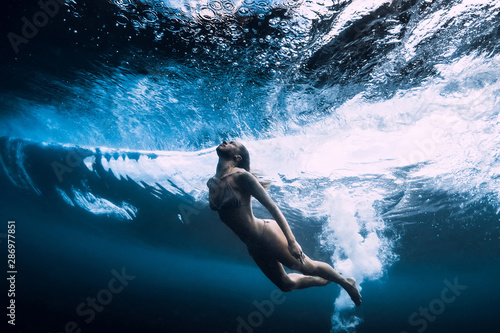 Woman in bikini dive without surfboard underwater with ocean wave. Duck dive under barrel wave © artifirsov