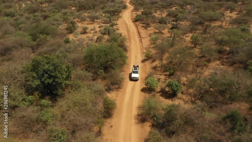 Africa outdoor travel and tourism - tilting drone shot of four wheel drive on unpaved dirt road, driving through desert in South Ethiopia