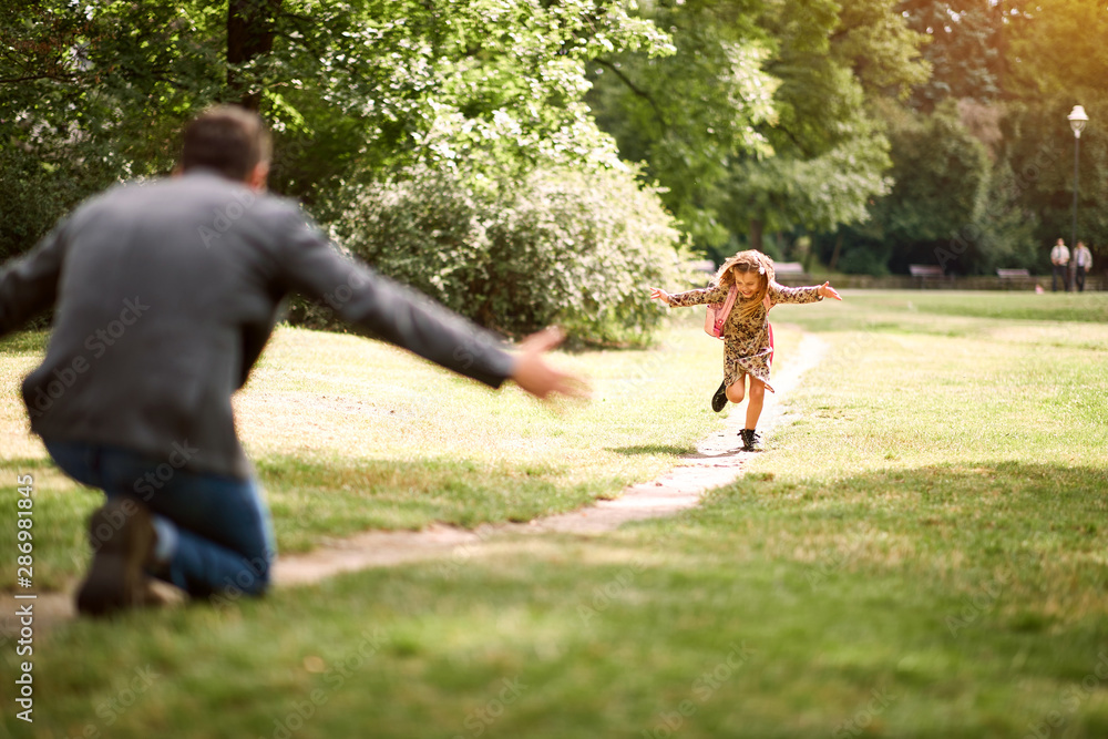 schoolgirl running to father to give him a hug after school. schoolgirl running to father to give him a hug after school.