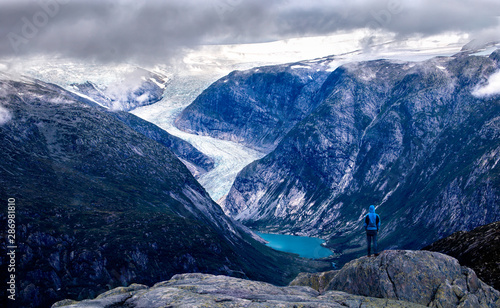 Hiker looking at nigardsbreen glacier from the summit of myrhyrna mountain in jostedalen, norway photo