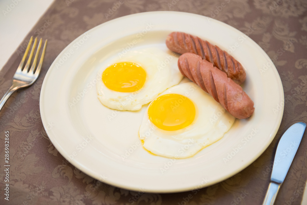 Fried eggs with sausages in a plate on the table. Fried eggs with sausages in a plate on the table.