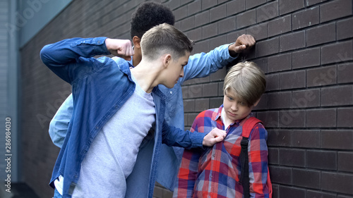 Cruel students threatening to punch junior boy, school bullying, intimidation photo