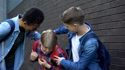 Cruel teenagers punching younger boy, physical intimidation, school bullying photo