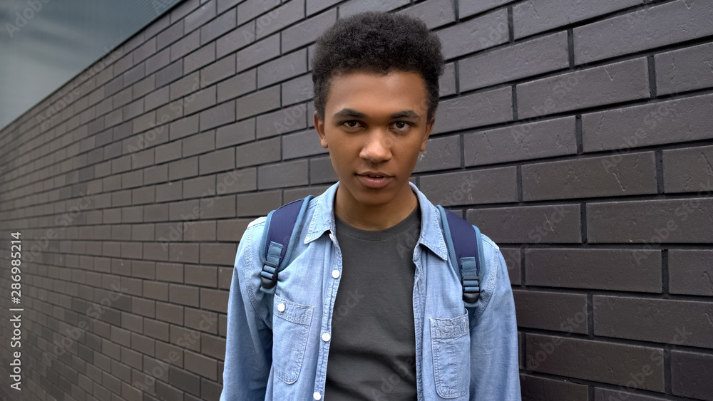 Obraz premium Afro-american schoolboy looking mockingly into camera, aggressive adolescent