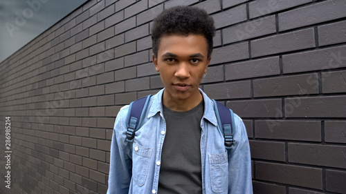 Afro-american schoolboy looking mockingly into camera, aggressive adolescent