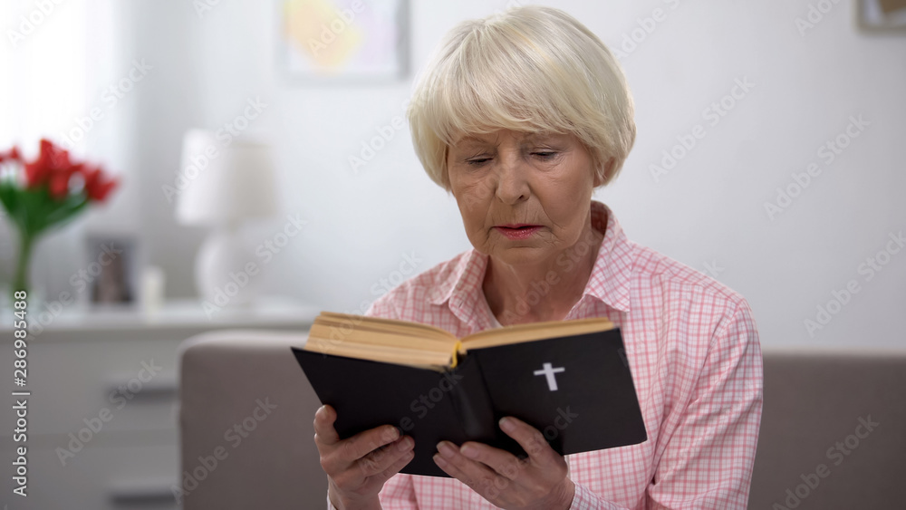 Religious senior woman reading holy bible at home, faith and belief concept Religious senior woman reading holy bible at home, faith and belief concept
