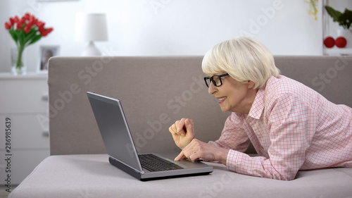 Happy old lady typing on laptop at home, work for senior people, freelance