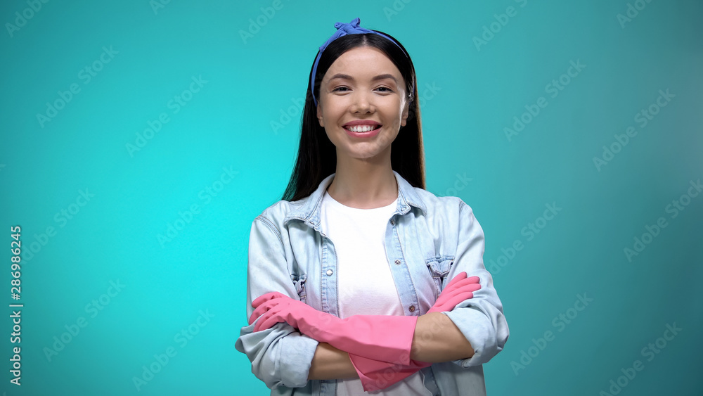 Confident housewife in gloves standing with hands crossed and smiling at camera Confident housewife in gloves standing with hands crossed and smiling at camera