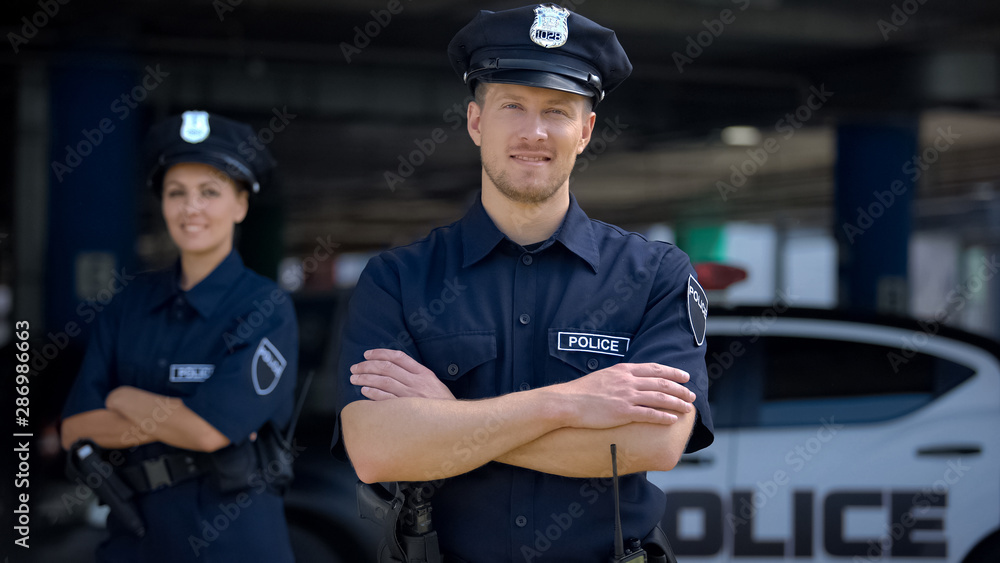 © motortion - Kind police officers smiling standing near police station, ready to help, order © motortion - Kind police officers smiling standing near police station, ready to help, order