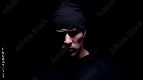 Burglar looking down, preparing to commit crime, isolated on black background