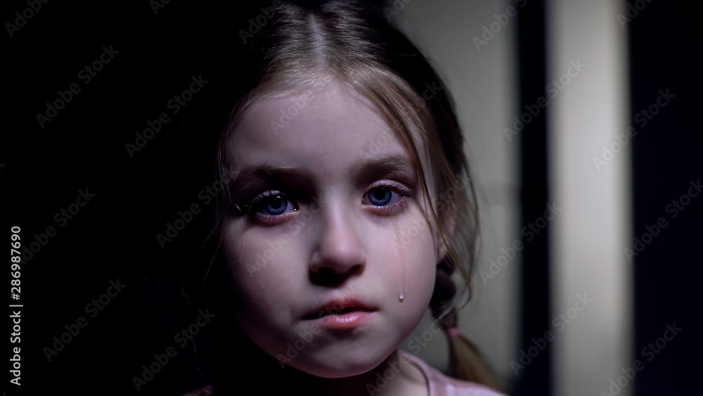 Little crying girl looking at camera, victim of domestic violence, childs rights Little crying girl looking at camera, victim of domestic violence, childs rights
