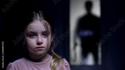 Bild auf Leinwand Frightened female kid crying on camera shadow of tyrant father with belt outside
