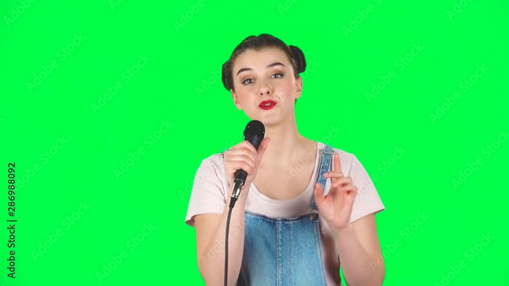 Attractive girl sings into a microphone and moves to the beat of music, slow motion Attractive girl sings into a microphone and moves to the beat of music, slow motion