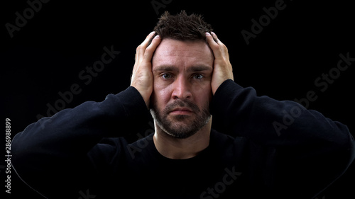 Tableau sur toile Desperate criminal repenting on dark background, feeling sorry, mental anguish