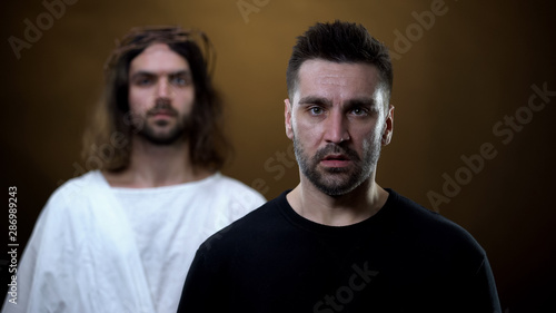 Sad man with messiah on background looking camera, spiritual support, faith
