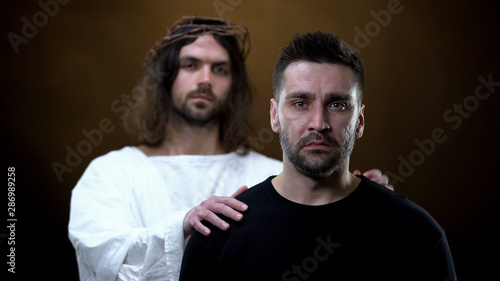 Fotografering Savior supporting crying man in trouble, spiritual redemption, divine will
