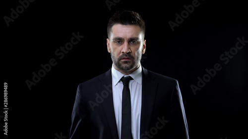Unhappy politician on black background, economic crisis, work disappointment