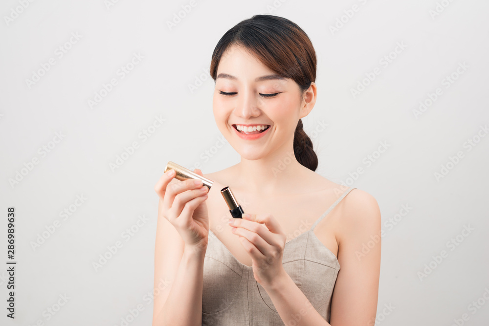 Photo of a beautiful young pretty asian woman with healthy skin posing naked isolated over white wall background holding lipstick. Photo of a beautiful young pretty asian woman with healthy skin posing naked isolated over white wall background holding lipstick.