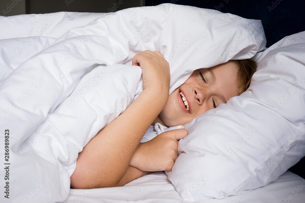 Young boy lies in bedroom and smiles Young boy lies in bedroom and smiles