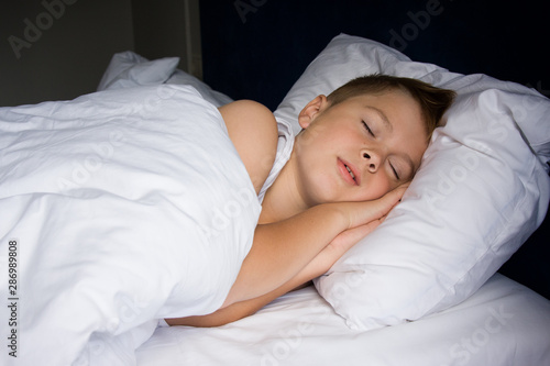 Tired young boy sleeping in bedroom