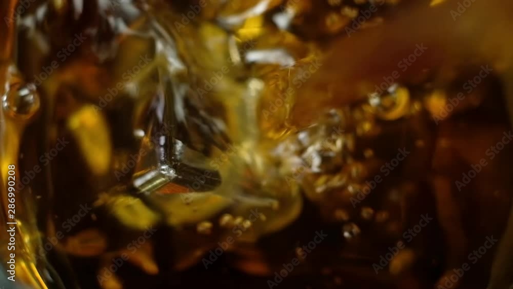 strong whiskey is slowly poured into a clear glass with large ice cubes. View from the top. Festive alcoholic drink. Happy weekend. strong whiskey is slowly poured into a clear glass with large ice cubes. View from the top. Festive alcoholic drink. Happy weekend.