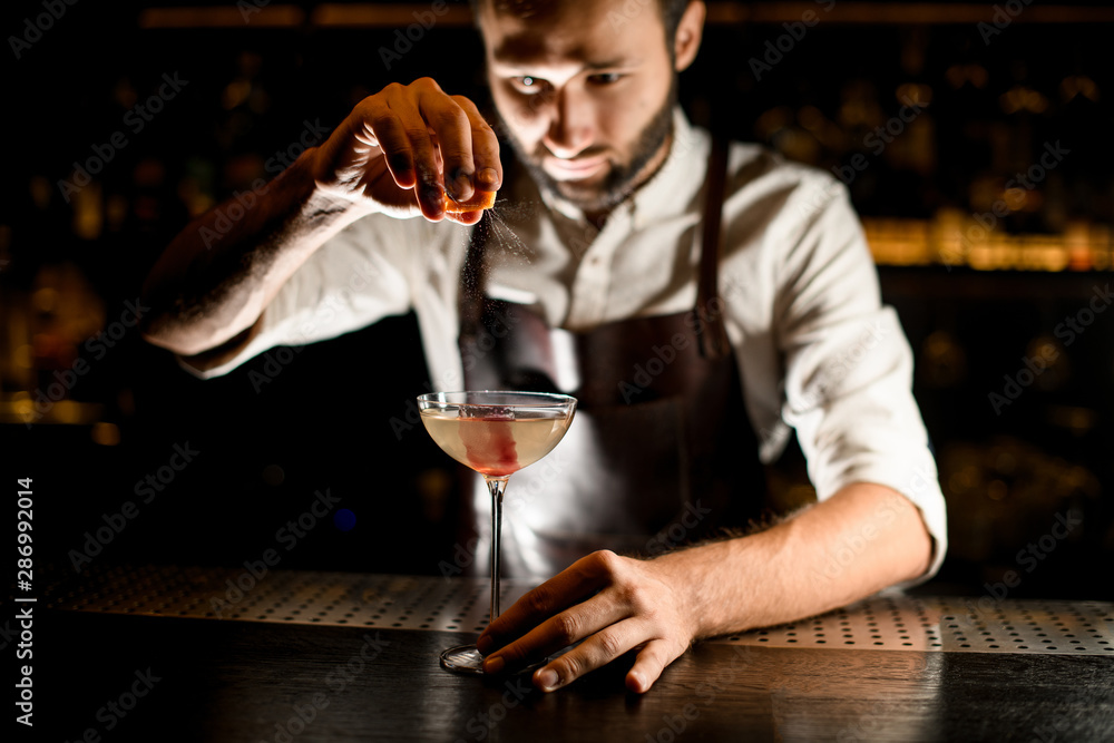 Male bartender serving a cocktail in the glass adding a lemon juice