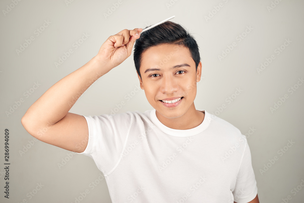 Portrait of smiling man in t-shrit combing his hair. Portrait of smiling man in t-shrit combing his hair.