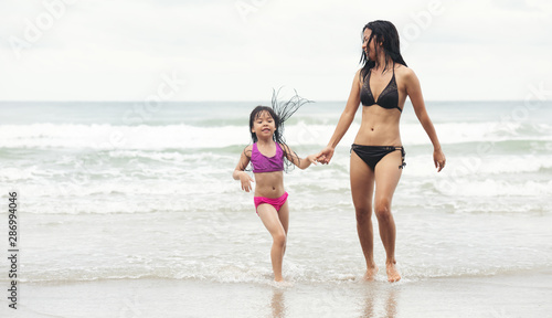 Happy little asia girl with her mother running on the beach.