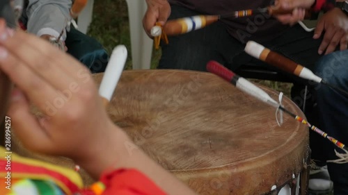 Native American men in a drum group hit drum at pow wow